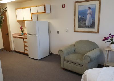 apartment with kitchenette, comfortable chair, and bed at Magnolia Gardens Senior Living