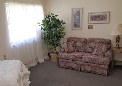 apartment with a love seat and bed at Magnolia Gardens Senior Living